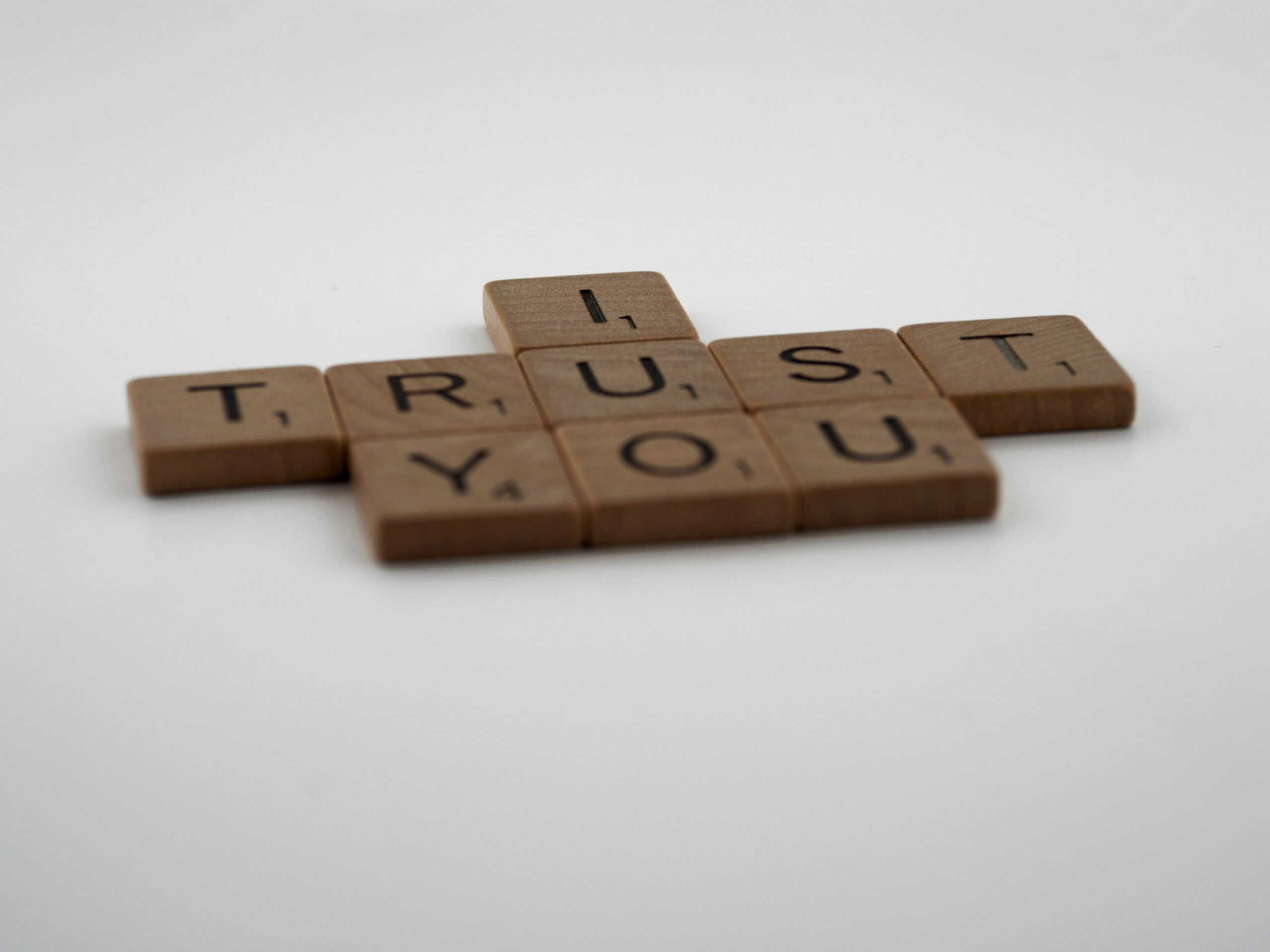 Scrabble tiles arranged on a white background to spell “I TRUST YOU.”