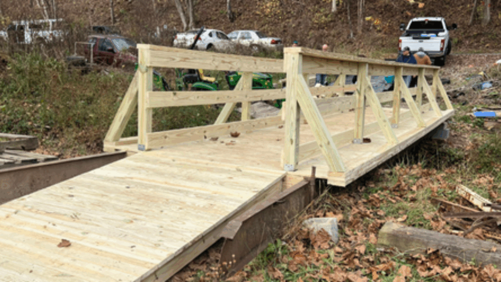 A newly rebuilt wooden bridge spanning a small creek, providing safe access for a rural West Virginia family and illustrating how churches and child welfare partners can close critical gaps for children and parents.